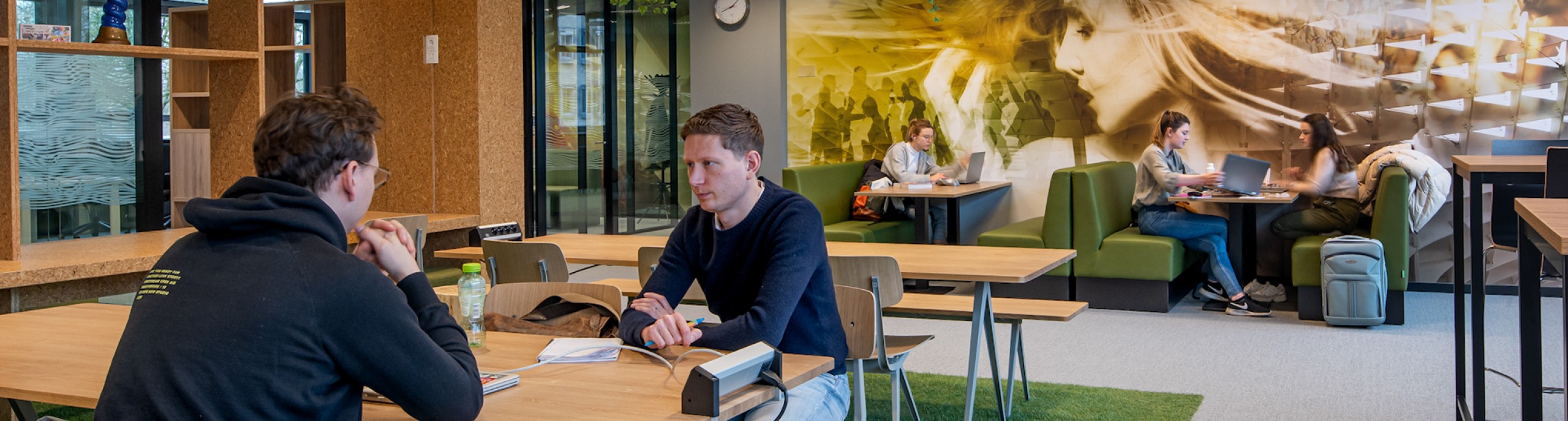 Studenten werken in een ruimte met tafels, stoelen en banken