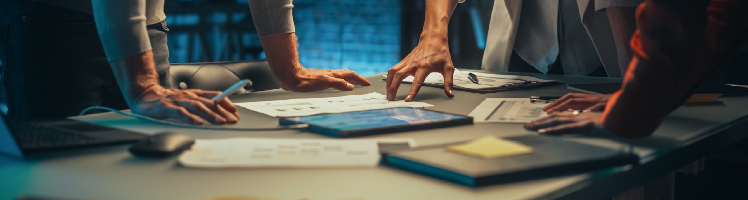 Drie mensen werken samen aan een tafel met papieren