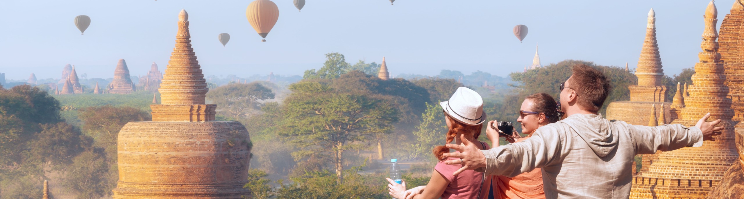 Drie toeristen kijken naar een lucht vol luchtballonnen 