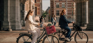 Twee meisjes fietsen langs het Rijksmuseum