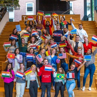 Groepsfoto van studenten die landsvlaggen vasthouden