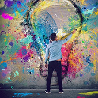 Een man schildert een gekleurde gloeilamp op een muur 