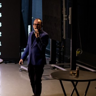 Een man geeft een presentatie voor een groot scherm met data