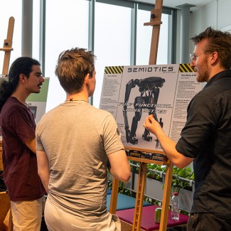 Een docent en twee studenten bekijken een project op een ezel