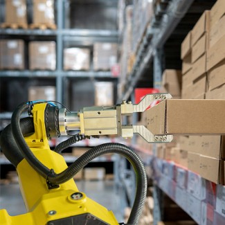 Een robot grijpt een kartonnen doos uit een stapel