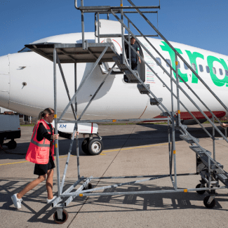 Een vrouw rolt een trap naar een vliegtuig 