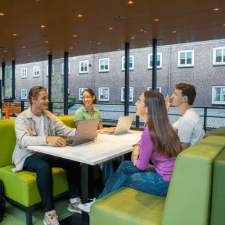 Vier studenten praten aan een tafel