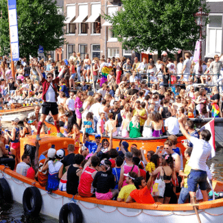 Dansende mensen op boten in de grachten tijdens Pride