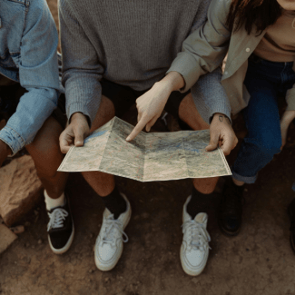 Drie zittende mensen bekijken een landskaart