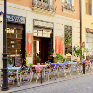 Stoelen en tafels van een Spaans restaurant staan op de stoep 