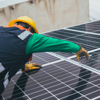 Een man installeert zonnepanelen op een dak
