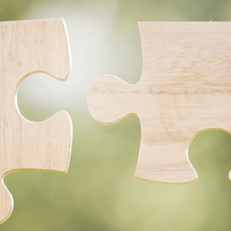 Twee handen houden twee puzzelstukken vast