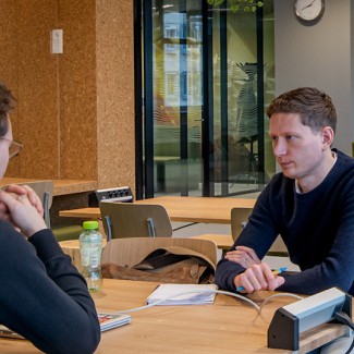 Studenten werken in een ruimte met tafels, stoelen en banken