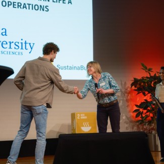 medewerker BUas geeft hand aan medewerker Groene Peper festival op een podium