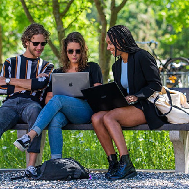 Drie studenten werken op een bankje op de BUas campus