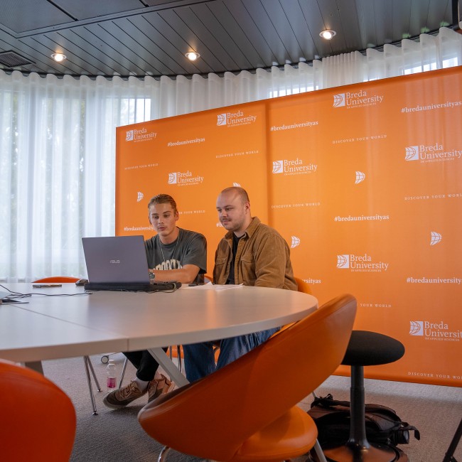 Twee studenten zitten voor een laptop voor de online open dag