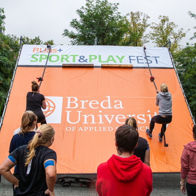 Twee studenten beklimmen een touw aan een muur