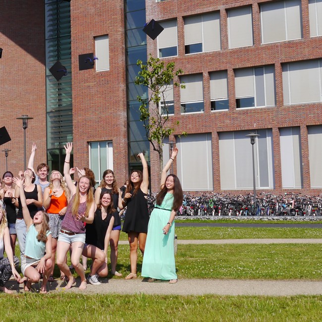 Afgestudeerde studenten gooien hun afstudeerhoed in de lucht