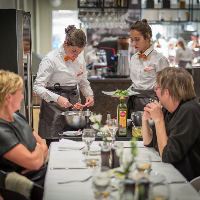 Twee studenten dienen een bord op in een restaurant