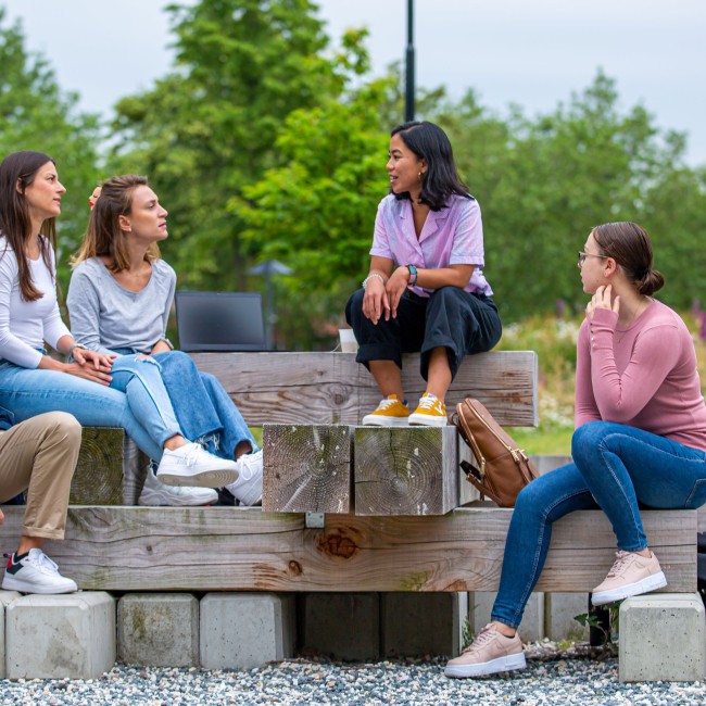 Vijf studenten zitten op een bank op de BUas campus