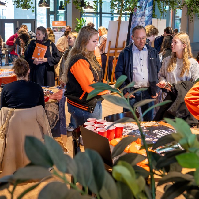 Studenten en docenten praten met bezoekers op de open dag