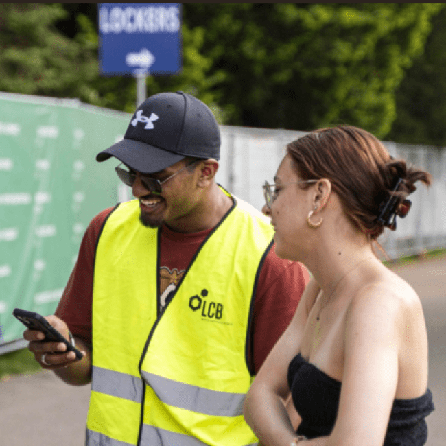 Twee meisjes staan bij een man in een geel hesje