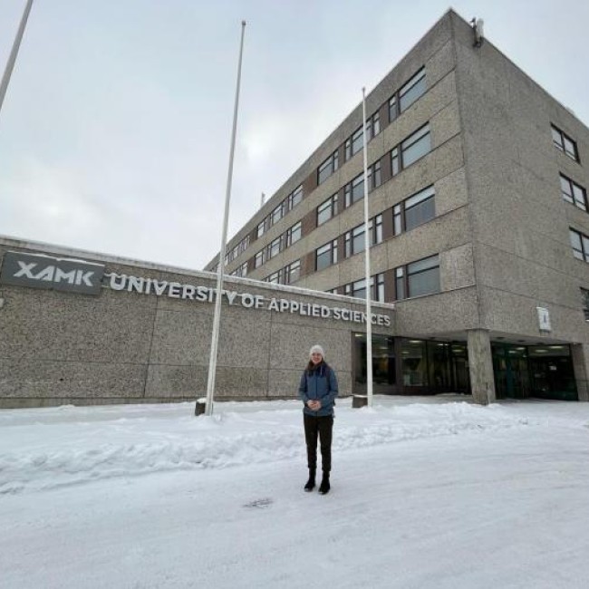 Een student staat voor de XAMK universiteit