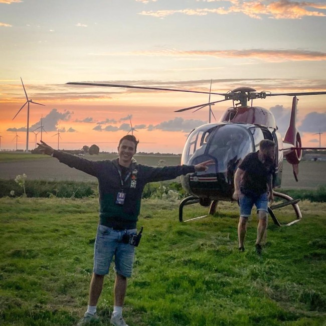 Sten Weenink staat in het gras naast een helikopter