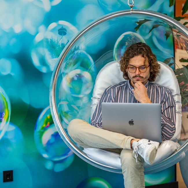 Student in een hangstoel werkt op een laptop