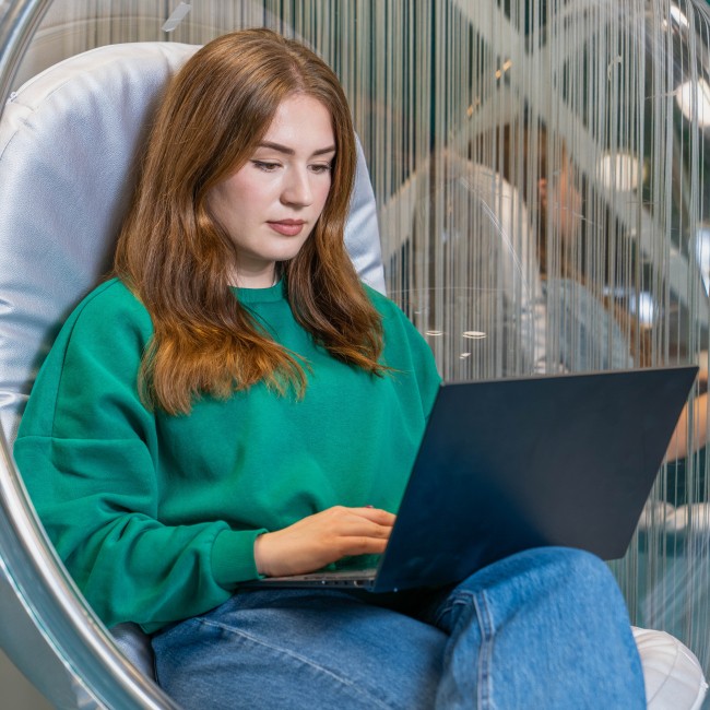 Student in een hangstoel met laptop op schoot