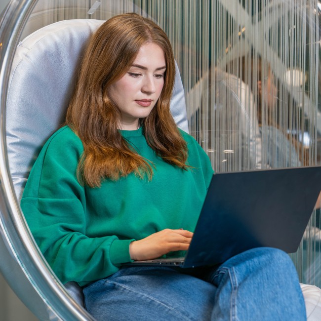 Student in een hangstoel met laptop op schoot