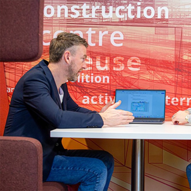 Een docent zit aan een tafel met een student 