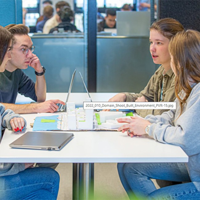 Vier studenten aan een tafel werken samen aan een project 