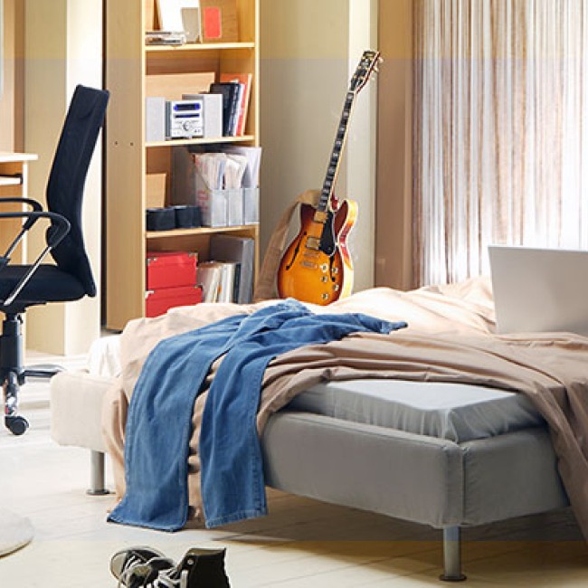 Een rommelige slaapkamer met een bed, bureau en stoel