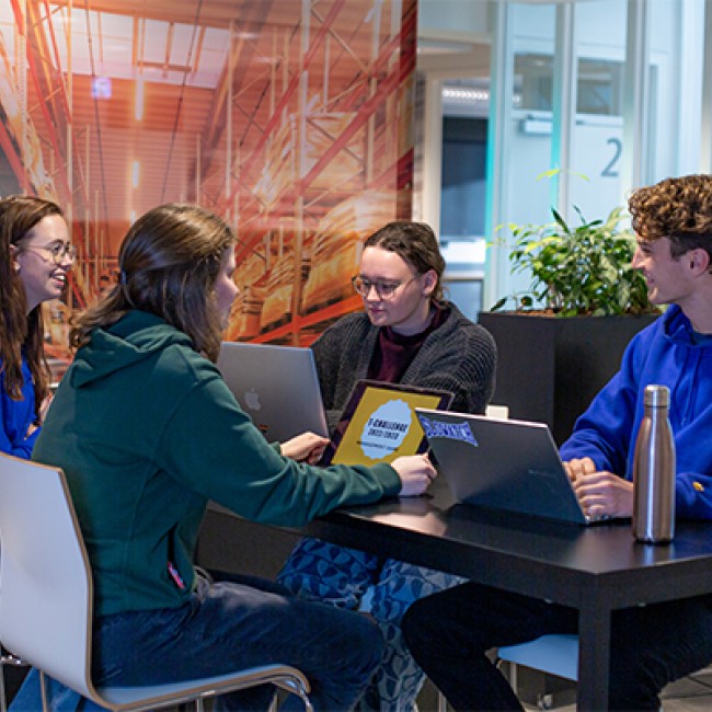 Vier studenten werken met hun laptop aan een tafel