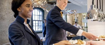 Twee horeca studenten geven een bord aan iemand anders