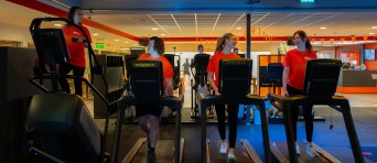 Vier studenten sporten op een loopband in een sportschool