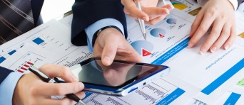 Twee mensen werken met een tablet en papieren met grafieken