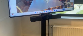 Een beeldscherm met mensen om een vergadertafel