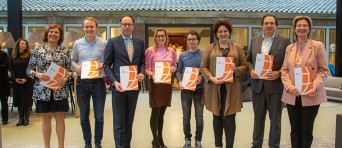 Groepsfoto van acht mensen met een document in hun handen