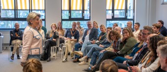 Een vrouw staat voor een groep zittende mensen