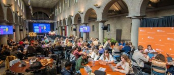 Studenten werken aan ronde tafels in een grote zaal