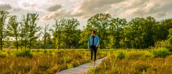 Een vrouw loopt over een vlonderpad in een bos