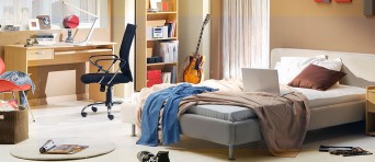 Een rommelige slaapkamer met een bed, bureau en stoel