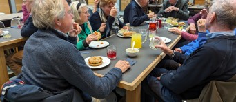 Ouderen lunchen samen aan grote tafels