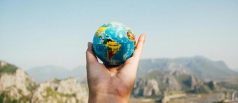 Een hand houdt een kleine wereldbol vast