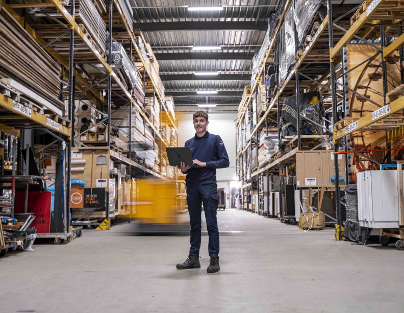 Man staat met laptop in een groot magazijn