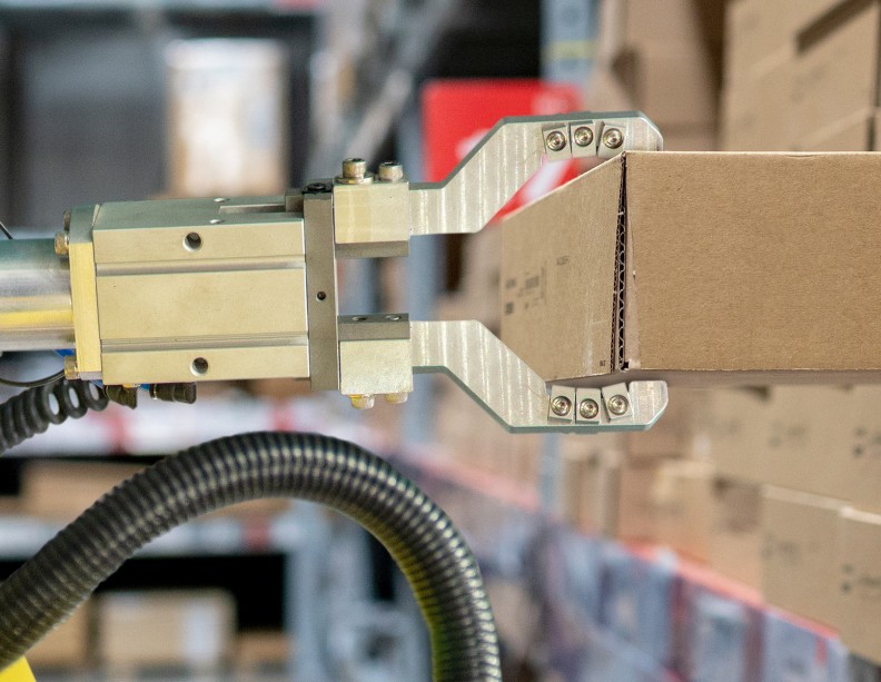 Een robot grijpt een kartonnen doos uit een stapel